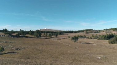 Mavi gökyüzü ve bulutlar karşı yeşil tepeler ile güzel iğne yapraklı ağaçlar. Fütüristik binaları ile bir tepede görüntülemek