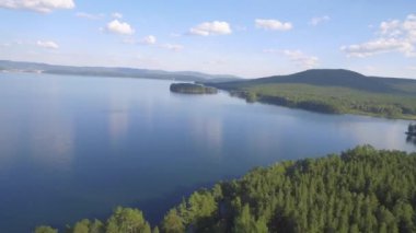 Ormanla çevrili uzak tropikal bir sahilin havadan görünüşü. Bereketli adaların ve gölün havadan görünüşü. Güzel Mavi Deniz Suyu 'nun üzerinde uçan dron. Muhteşem Panoramik Peyzaj 4K