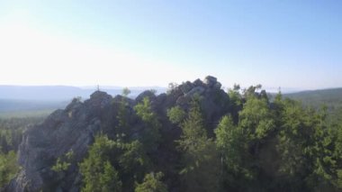Firavun 'un tepesindeki kayaların üzerindeki firavun ağacı ormanı, yukarıdan görünen kayaların üzerindeki huş ve çam ağaçları. Etrafı kaya ve ormanlarla çevrili güzel bir yaz manzarası, hava manzarası 4K