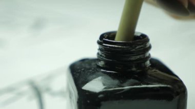 Yansıtıcı mürekkep yüzeyine batırılmış Çin fırçası ucu siyah kavanoza. Fırça ve mürekkebe yakın. Çince mürekkep 4K kaligrafi fırçaları