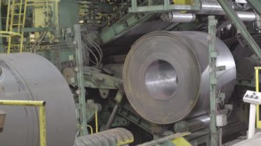 Metal bobin makinesi. Fabrikadaki makine. Depoda yuvarlanan çelik levha, soğuk rulo çelik bobin 4K