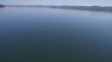 Sakin orman gölü üzerindeki hava manzarası, ağaç ormanı arka planları. Göl kıyısındaki ağaçların havadan görünüşü. Yansımaları 4K olan orman gölü manzarası