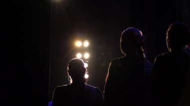 Sahne ışıkları altındaki aktörlerin silueti. Sanatçılar sahne arkasındalar. Modern performans 4K