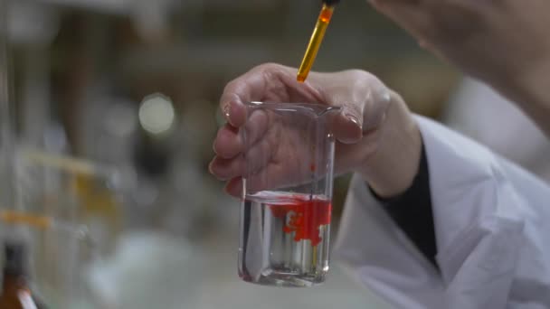 化学家手中的红颜色在试管中混合的物质 医生倒红化学品进入在烧瓶 关闭了 — 图库视频影像