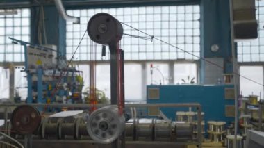 Dönen bobinleri ve kablosu olan bir endüstri makinesi. Yaratıcı. Makine aletlerindeki kabloların ve kabloların endüstriyel sarılması. Otomatik makineler. Fabrikada kablolar var.. 