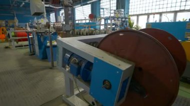 Fabrikada kablolarla dönen bobin. Yaratıcı. Üretim makinesindeki kabloyu bobine sarmak. Metalurji tesisinde kablo sarma işlemi. 