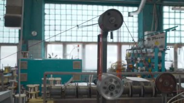 Dönen bobinleri ve kablosu olan bir endüstri makinesi. Yaratıcı. Makine aletlerindeki kabloların ve kabloların endüstriyel sarılması. Otomatik makineler. Fabrikada kablolar var.. 