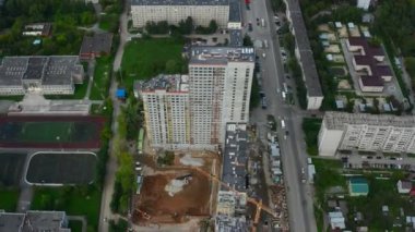 Şehirdeki çok katlı binanın en üst manzarası. Stok görüntüleri. Yaz günü şehir merkezindeki çok katlı binanın inşaatı. Modern şehrin gökdelenli manzarası