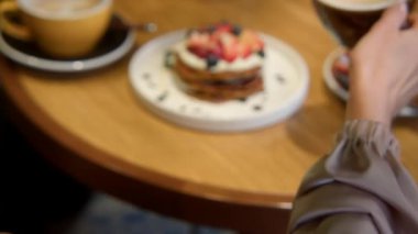 Kafede kahve ve tatlıyla yemek yiyen güzel bir kadının yakın çekimi. Stok görüntüleri. Kafede güzel bir tatlıyla kahve içen bir kadın. Güzel bir estetik öğle yemeği, tatlı ve kafede kahve.. 