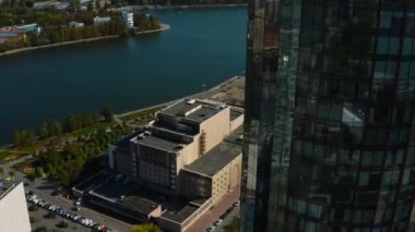 Şehir ve nehir manzaralı yüksek binaların cam cephe manzarası. Stok görüntüleri. Camdan binaları olan modern şehrin güzel manzarası. Yeşil manzaralı cam gökdelenler.