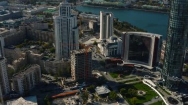 Şehir merkezinde yüksek binaları olan bir binanın en üst görüntüsü. Stok görüntüleri. Şehir manzarası, yüksek binalar ve merkezde inşaat halindeki binalar. Güzel yaz.