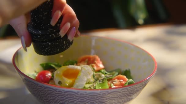 샐러드에 향신료를 여자의 클로즈업 비디오 달걀과 샐러드 아름다운 샐러드 그릇에 — 비디오