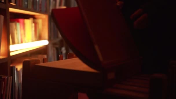 신비한 남자의 클로즈업 비디오 사람은 번쩍이는 빛으로 어두운 도서관에서 엽니다 — 비디오