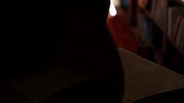 Büyük, gizemli bir kitap okuyan adam. Stok görüntüleri. Kütüphanede antik yasaklı kitapları okuyan gizemli bir adamın yakın çekimi. Gece kütüphanesinde kitapları olan gizli bir topluluk.. 
