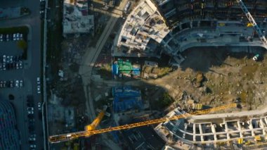 Stadyumun en üst manzarası. Stok görüntüleri. Şehir merkezinde vinçleri ve makineleri olan bir inşaat alanı. Güneşli yaz gününde şehirde spor arenası inşaatı. 