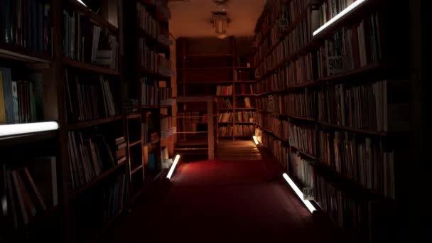 点滅するライトが付いている夜の図書館 ストック映像 夜の図書館での本棚付きの回廊 夜の図書館の本棚間の通路の点滅ライト — ストック動画
