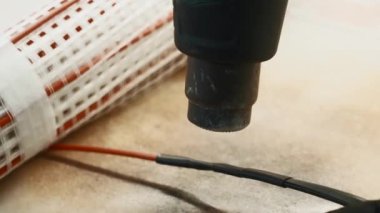 Usta elektrikçi bakır kabloların etrafında özel bir aletle yalıtım yapıyor. Yaratıcı. Atölye ve ekipman detayları