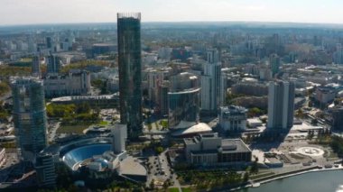 Güneşli bir günde nehri olan güzel, modern bir şehir manzarası. Stok görüntüleri. Güneşli yaz gününde yüksek binaları olan güzel bir şehir manzarası. Gökdelenleri ve nehri olan modern şehirde yaz mevsimi. 