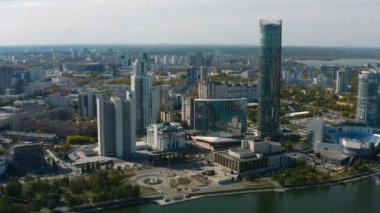 Güneşli bir günde nehri olan güzel, modern bir şehir manzarası. Stok görüntüleri. Güneşli yaz gününde yüksek binaları olan güzel bir şehir manzarası. Gökdelenleri ve nehri olan modern şehirde yaz mevsimi. 