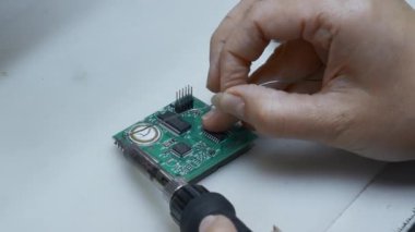 Servis merkezinde bilgisayar parçaları tamir eden genç bir adam. Yaratıcı. Çipi lehimlemeye yakın tut.