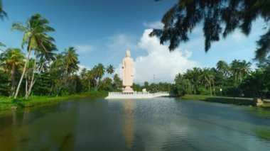 Tsunami Honganji Vihara, Hikkaduwa, Sri Lanka. Başla. Yeşil palmiye ağaçları ve mavi bulutlu gökyüzü arasında güzel beyaz heykel