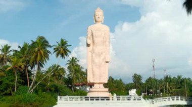Tsunami Honganji Vihara, Hikkaduwa, Sri Lanka. Başla. Yeşil palmiye ağaçları ve mavi bulutlu gökyüzü arasında güzel beyaz heykel