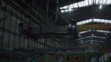 Fabrikadaki süspansiyonlar hakkında geniş bir metal parçasının düşük açılı görüntüsü. Şarjör. Fabrikada yük taşımak için çapaları olan askıya alma sistemleri