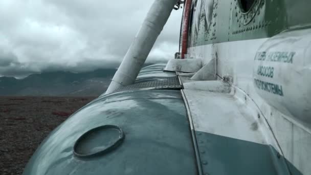 丘の上の古い錆びた飛行機の近くに クリップ バックグラウンドの重い雲と山で航空機の外観の詳細 — ストック動画
