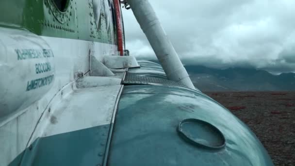 丘の上の古い錆びた飛行機の近くに クリップ バックグラウンドの重い雲と山で航空機の外観の詳細 — ストック動画