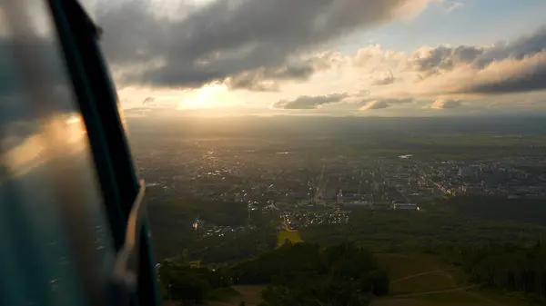 stock image Top view from cab of cable car on town. Clip. Beautiful landscape on small town in green valley on sunny day. Sunny view opens from rising cab of cable car.