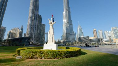 Camera moving towards sculpture with hand gesture: win, victory, love. Action. architecture and nature of sunny Dubai clipart