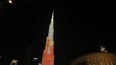Dubai - United Arab Emirates: June 5, 2023: light show at Burj Khalifa, the highest tower, covered with arty animated illumination. Action. Modern city center clipart