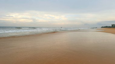 Uzun dalgaları ve mavi bulutlu gökyüzü olan güzel kumlu bir sahil manzarası. Başla. Tropikal adasında güzel sakin bir sahil