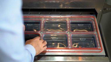 Plastik ambalaj üretimi, endüstriyel arka plan. Medya. Yöneticinin ellerini kapat plastik küçük kutuların kalitesini kontrol et, kalite denetimi