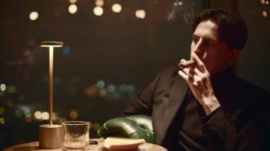 Genç adam zarif bir şekilde puro içiyor. Medya. Yakışıklı adam restoranda puro içiyor. Restoranda sigara içen sinematik bir puro.. 