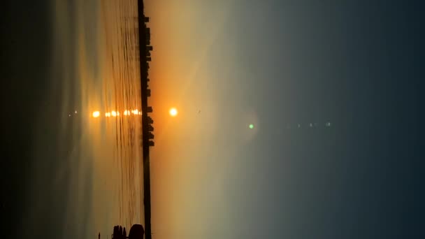 地平线上的天空五彩斑斓 女人站在浪板上航行 女子在夕阳西下享受河上航行的纵向照片 — 图库视频影像