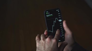 Kripto para işlem şeması cep telefonu. Medya. Adamın telefonundaki döviz çizelgesine yakından bakıyor. Telefonunuzdaki borsa kripto para birimi şeması.