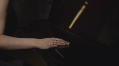 Kadının yakın çekimi piyano çalmaya başlar. Medya. Zarif bir kadın restoranda piyanoda caz çalmaya başlar. Şık elbiseli kadın piyano konseri çalmaya başladı.. 