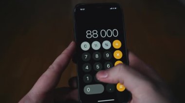 Telefonda çoğalan bir adama yakın çekim. Medya. Adam telefonda muhasebe faturalarını sayıyor. Telefondaki hesap makinesine güveniliyor. 