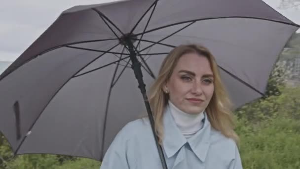 Junge Blonde Frau Mit Grauem Regenschirm Draußen Auf Der Grünen — Stockvideo
