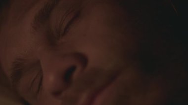 Genç sakallı adamın gözlerini kapayıp mum ışığında karanlık bir odada uykuya dalması. Medya. Dalgın bir adam yalan söylüyor ve geceleri içeride uyuyor.