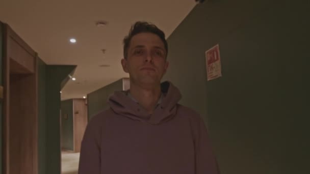 ホテルの建物の廊下を歩いている青年 ストッククリップ フーディーを着ているホールの男 — ストック動画