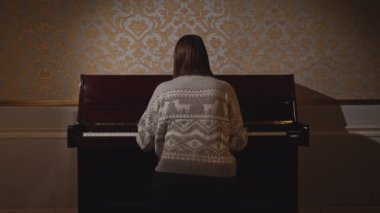 Genç kadın piyanoyu kapatıp gidiyor. Medya. Piyanoyu kapatıp giden kadının arka görüntüsü. Kadın ne yazık ki eski piyanoyu kapattı.. 