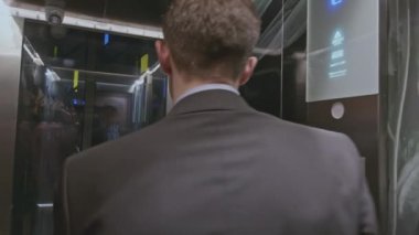 Bir grup iş adamı modern asansöre giriyor ve şirket toplantısını tartışıyor. Borsa klipsi. İş adamları iş merkezinin üst katına çıkmak için asansör kullanıyor.