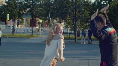 Mutlu genç çift bir yaz günü sokakta dans ediyor. Hisse. Aşık bir adam ve bir kadın şehir meydanında dans edip eğleniyorlar.