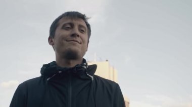 Adam çatıdan intihar etti. Hisse. Çatıda intihar sahnesini oynayan aktörün sinematik çekimi. Adam gülümsüyor ve binanın çatısından düşüyor.. 