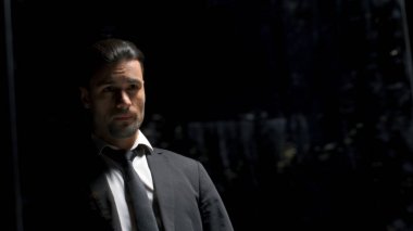 Siyah arka planda takım elbiseli bir adamın aynadaki yansıması. Stok görüntüleri. Takım elbiseli adam aynanın önünde bir şeye hazırlanıyor. Aynada takım elbiseli bir adamın yansıması olan tiyatro yapımı..