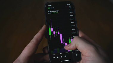 Finansal çizelge telefonda. Medya. Adamın şifreli para birimini telefon diyagramında görüntülediği yakın plan. Kripto Para Birimi ve Borsa Çizgileri.