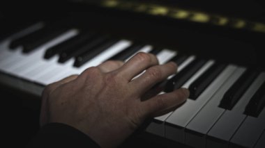 Piyano çalarken yakın plan. Medya. Piyano çalarken ışık düşmeye başladı. Yalnız el piyanoda notalar çalıyor..