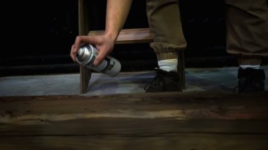Ahşap kiriş boyayan adam, yaklaş. Medya. Erkek işçi kütüğü boyamak için siyah renkli sprey boya kullanıyor.